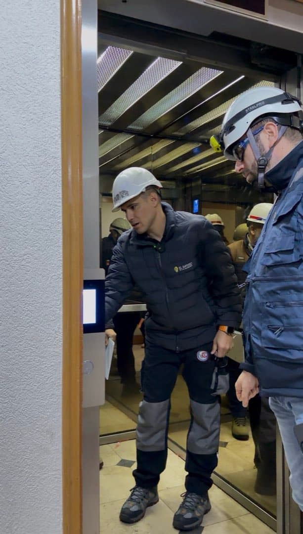 Equipo técnico trabajando en la puerta de piso de un ascensor
